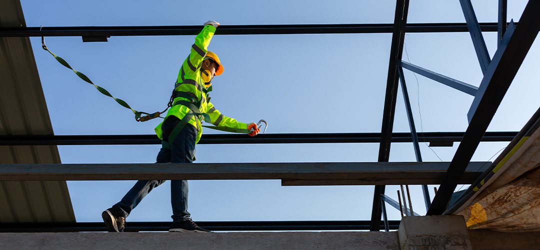 Profissionais da construção civil trabalhando em altura com sistemas de proteção contra quedas em obra.